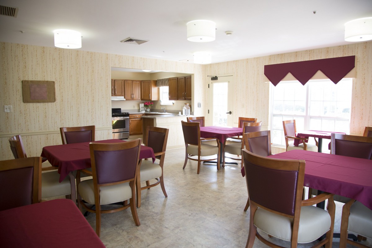 A spacious dining area with multiple tables and chairs adjacent to a kitchen.