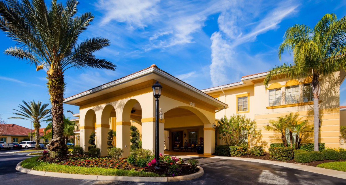 Entrance to a hotel with a clear blue sky and landscaped surroundings.