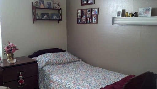 A cozy bedroom featuring a neatly made bed and personal photographs displayed on the wall.