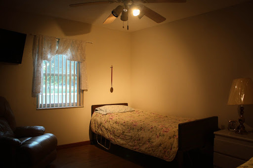A cozy bedroom featuring a bed, window with curtains, and a ceiling fan.