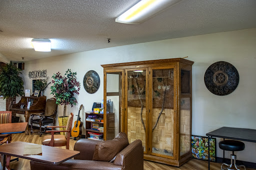 A cozy living room featuring a wooden cabinet, comfortable seating, musical instruments, and decorative elements.