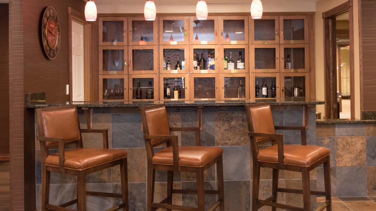A cozy bar area with wooden chairs and a well-stocked counter.