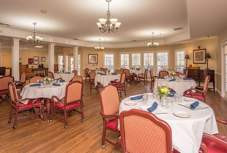 An elegant dining room with neatly arranged tables and chairs, set for a meal.