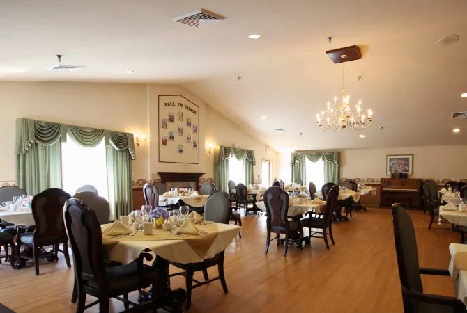 An elegant dining room with set tables, chandeliers, and decorative curtains.