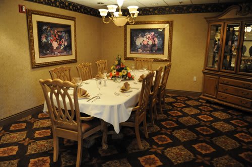 An elegantly decorated dining room with a table set for a meal, surrounded by chairs and adorned with framed artwork on the walls.