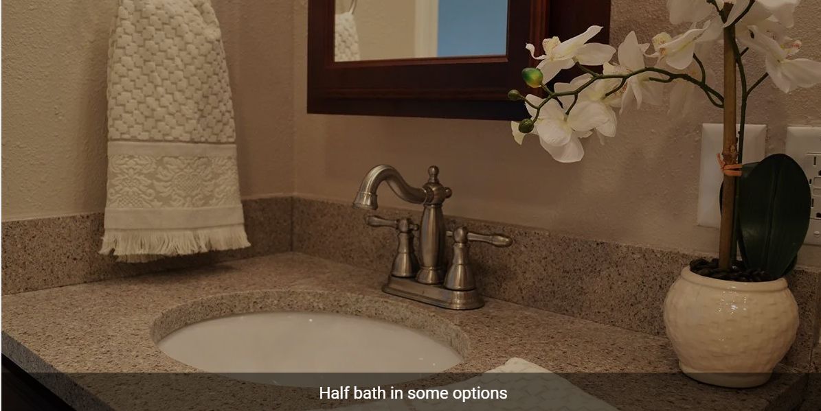 A half bathroom featuring a sink with a stylish faucet, a mirror, and decorative flowers.