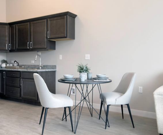 A modern kitchen with a minimalist dining area featuring a round table and two chairs.