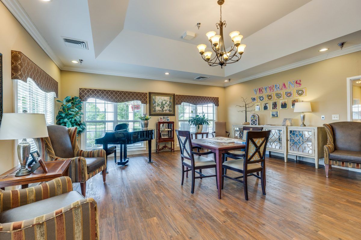 A well-decorated room with a grand piano, wooden flooring, and elegant furnishings.