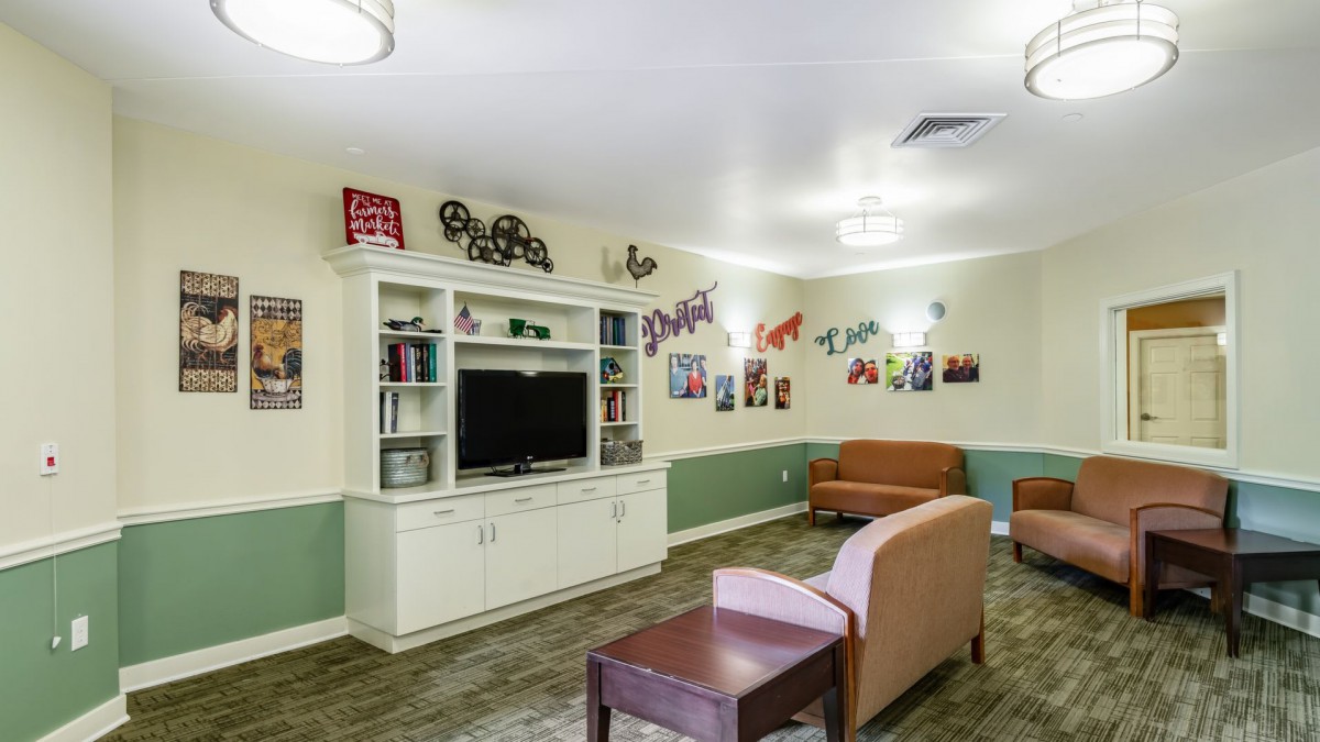 A cozy living room with a TV, sofas, and colorful wall decorations.