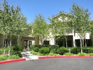 A residential building surrounded by trees and landscaped greenery.