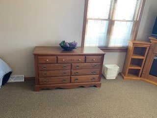 A wooden dresser with multiple drawers in a well-lit room.