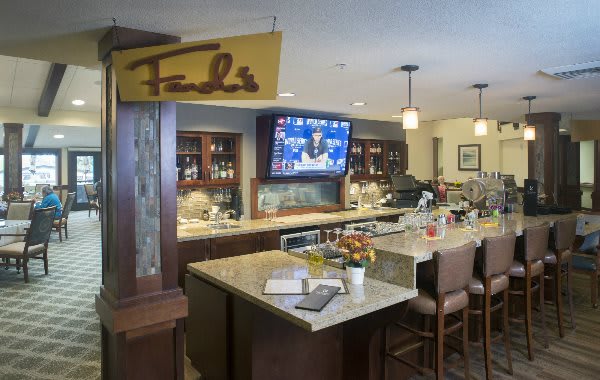 An inviting bar area with seating, a television, and a variety of drinks on display.