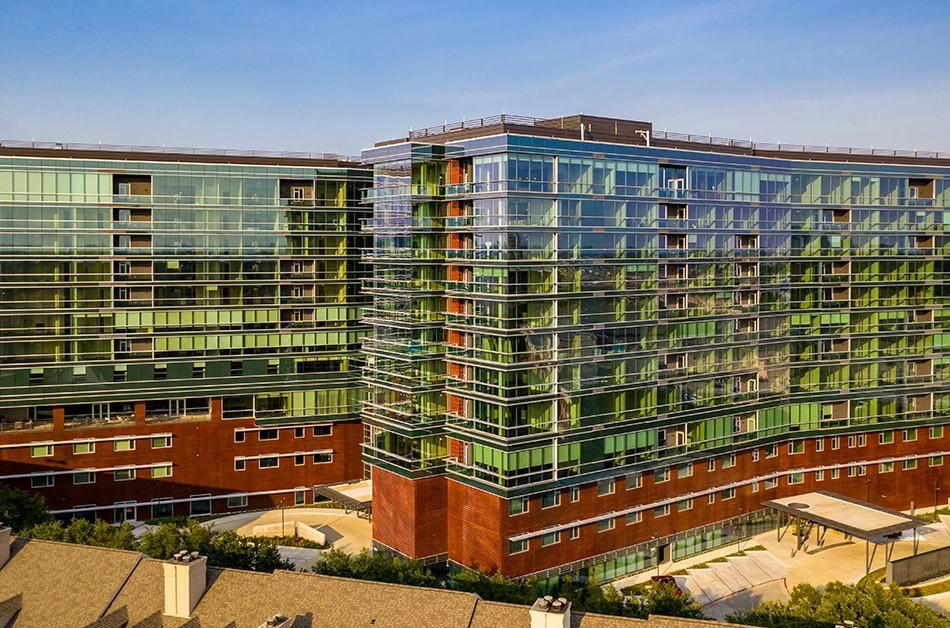 Modern office building with a striking glass facade against a clear sky.