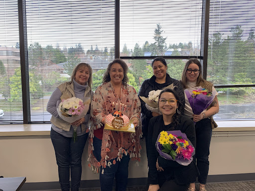 A joyful celebration with colleagues, surrounded by flowers and smiles.