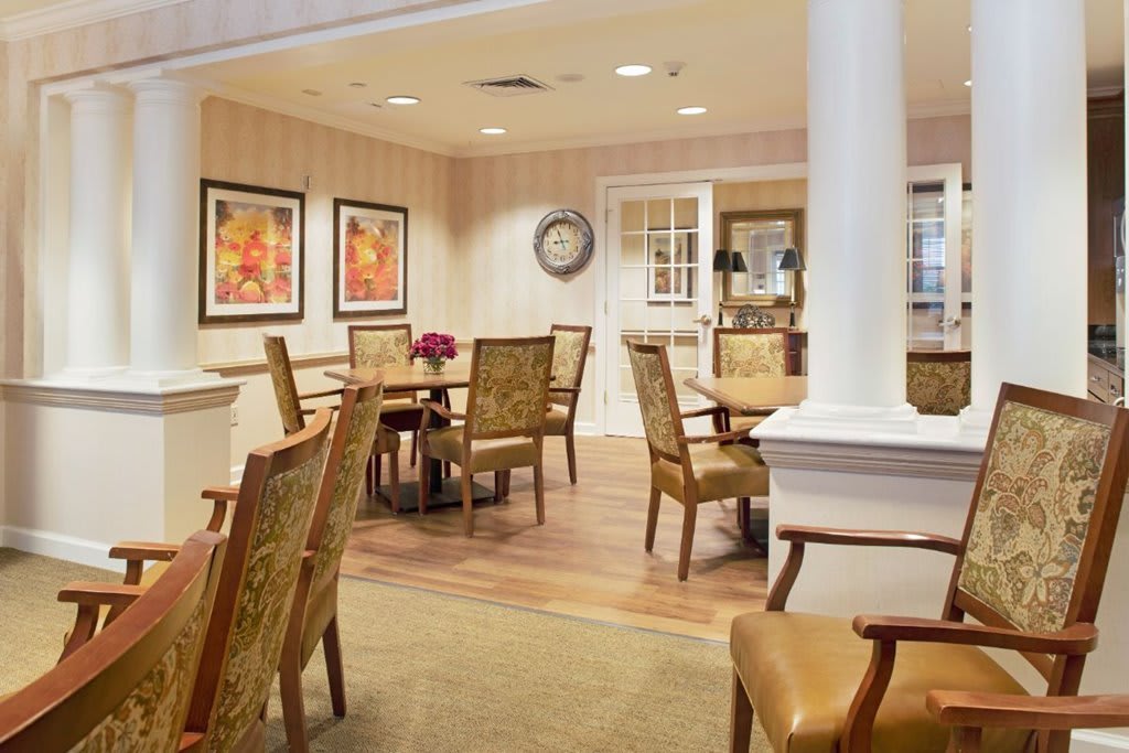 A cozy dining area with wooden chairs and tables, decorated with framed artwork on the walls.