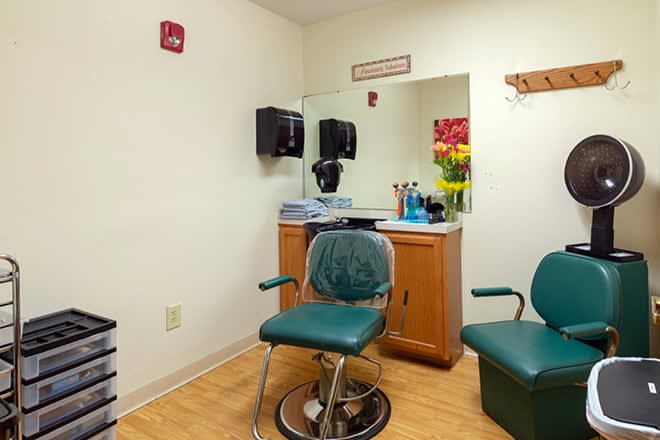 An empty hair salon with a hair cutting chair, mirror, and barber tools.