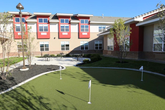 A modern building with a small outdoor putting green in the foreground.