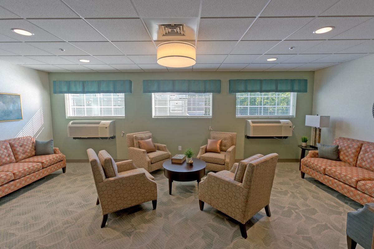 A cozy seating area with beige armchairs arranged around a circular table in a well-lit room.