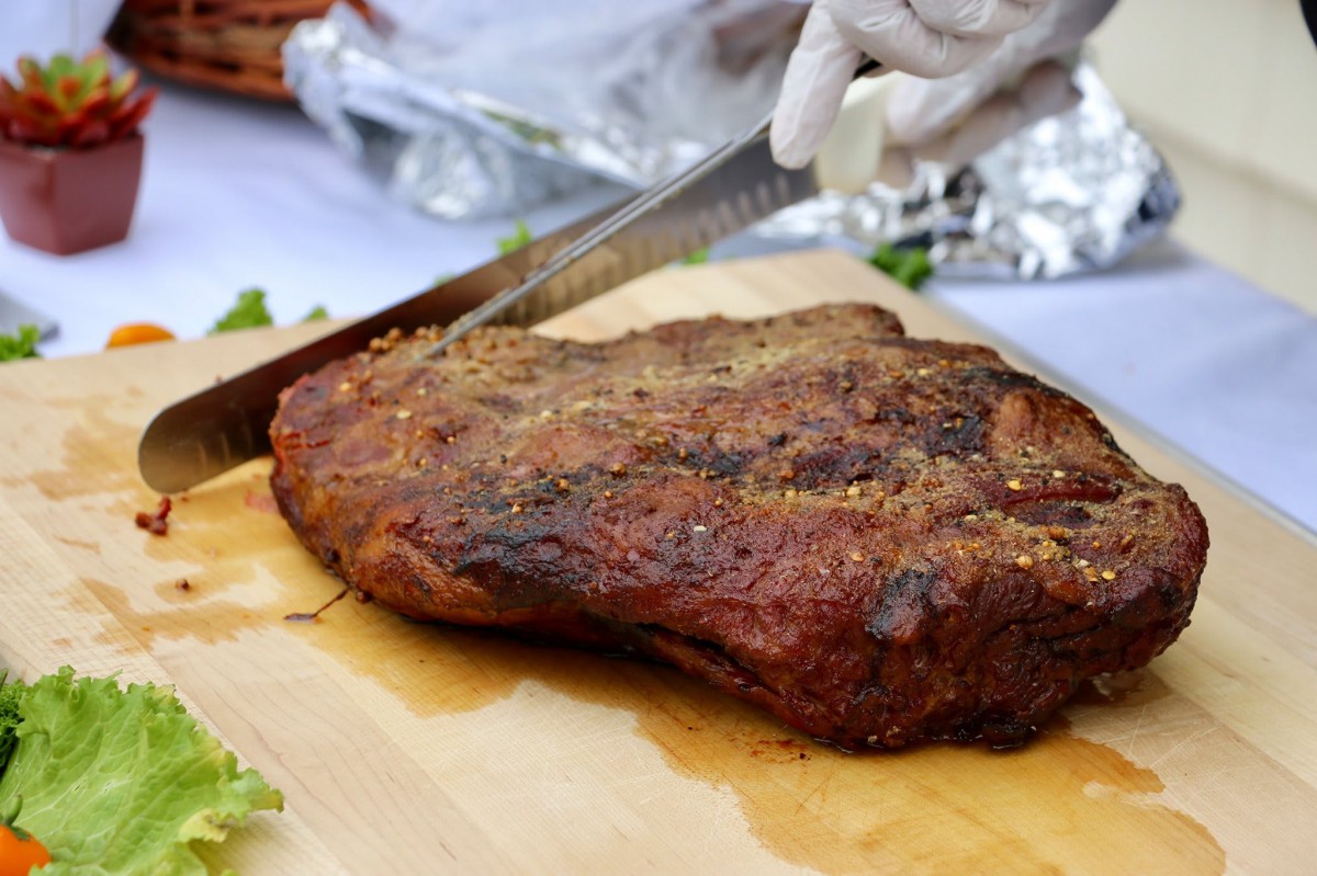 A well-seasoned brisket being sliced on a cutting board.