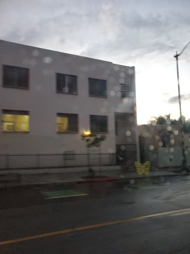 A rainy evening view of a building through a wet window.