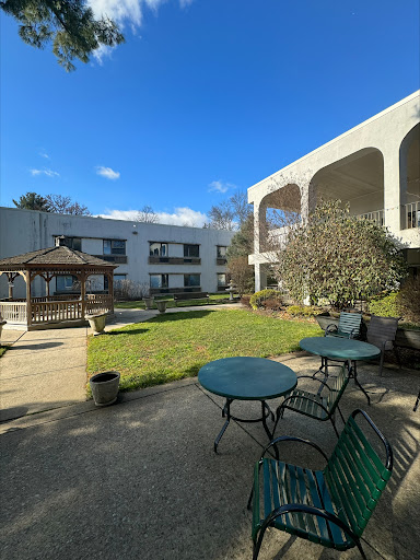 A serene courtyard featuring a gazebo and seating arrangements under a clear blue sky.