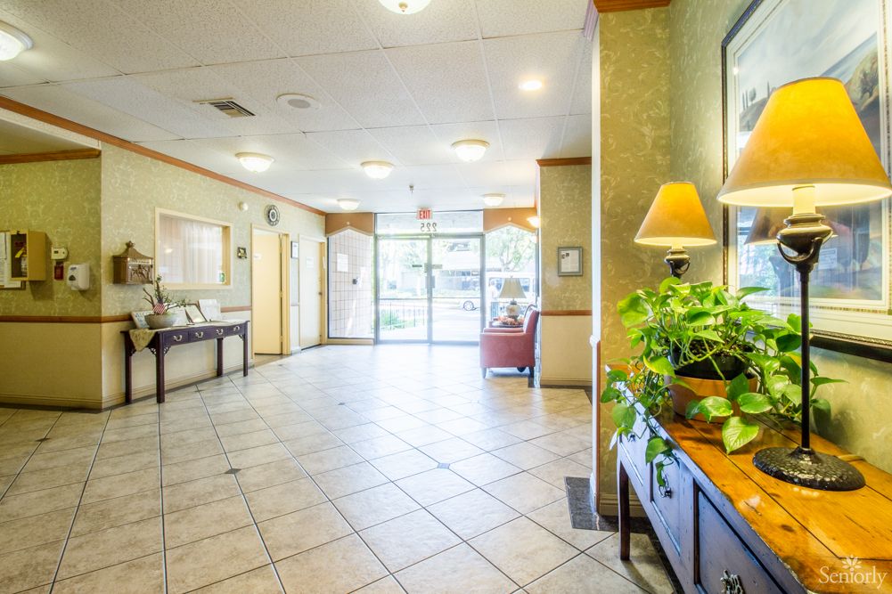 A bright lobby area with tiled floors, plants, and cozy furniture.