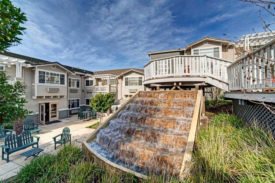A modern apartment complex featuring a cascading water feature and outdoor seating area.