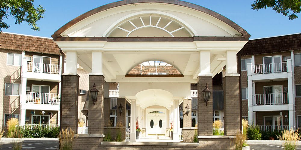 A grand entrance with brick walls and white columns, featuring a decorative archway.