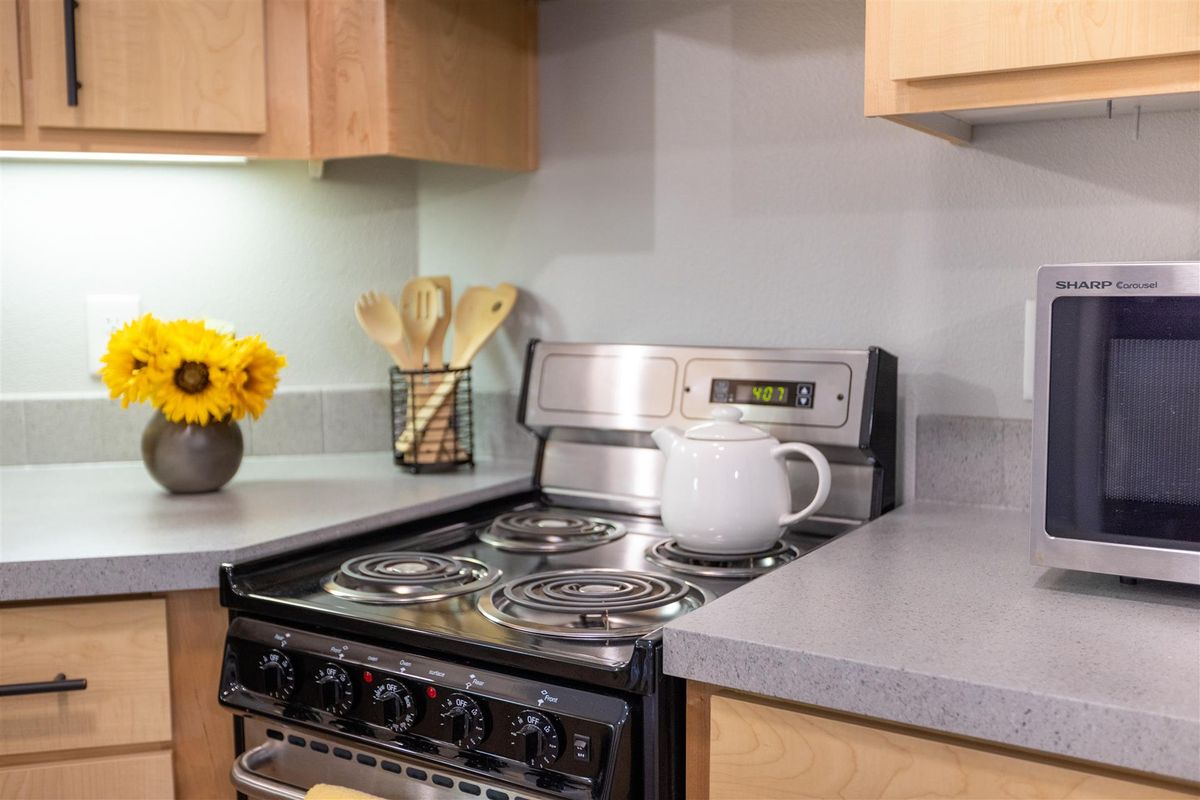 A cozy kitchen setup with a stove, teapot, and decorative utensils.