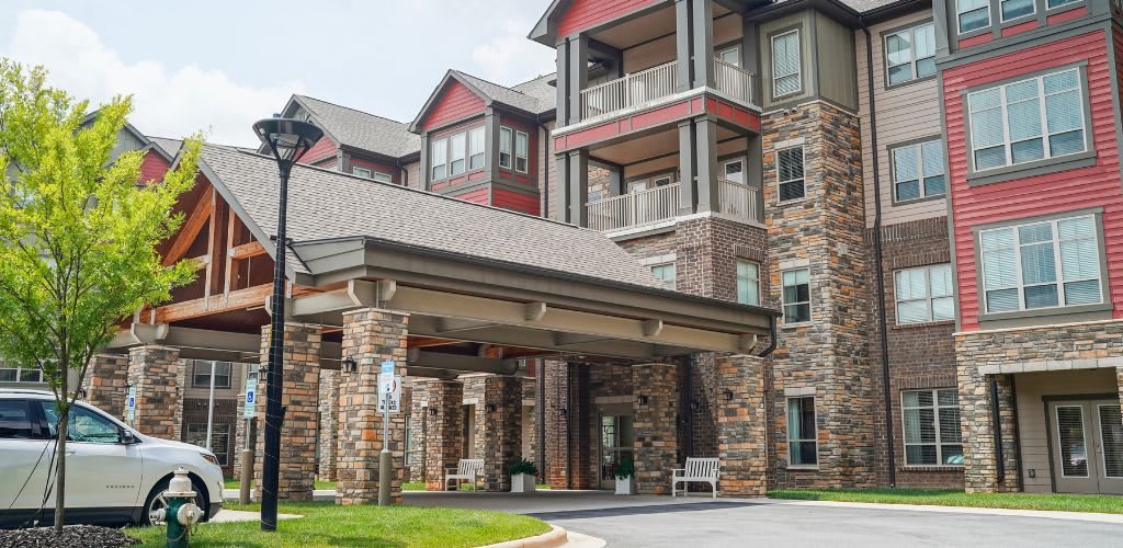 A modern apartment complex with a stone facade and covered entrance.