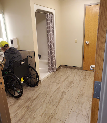 A spacious bathroom designed for accessibility, featuring a wheelchair and a shower area.