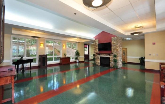A spacious and modern lobby featuring a fireplace and television, illuminated by natural light.