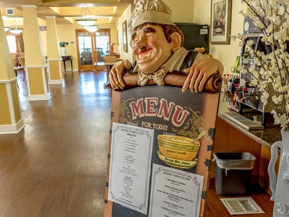 A decorative chef statue holding a menu sign in a hallway.