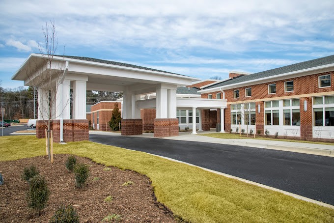 A modern building with a covered entrance and landscaped surroundings.