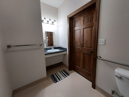 A view of a neatly designed bathroom featuring a sink, mirror, and wooden door.