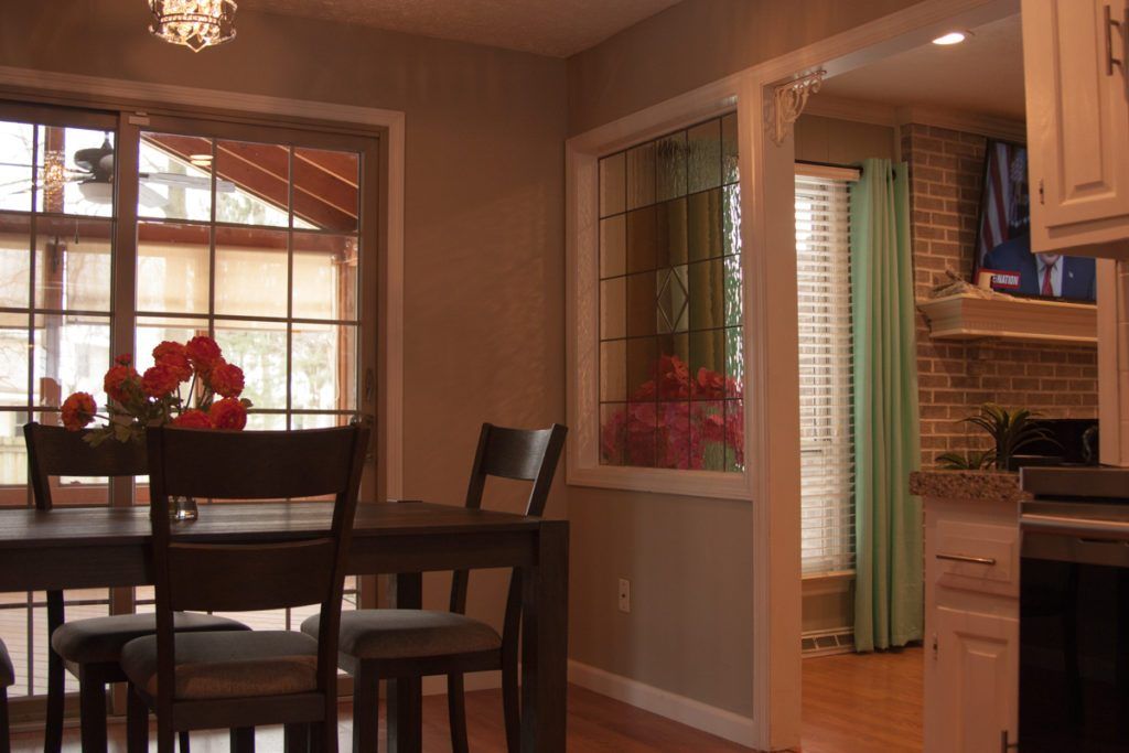 A cozy dining area with a dark wooden table and chairs, featuring large windows that let in natural light.