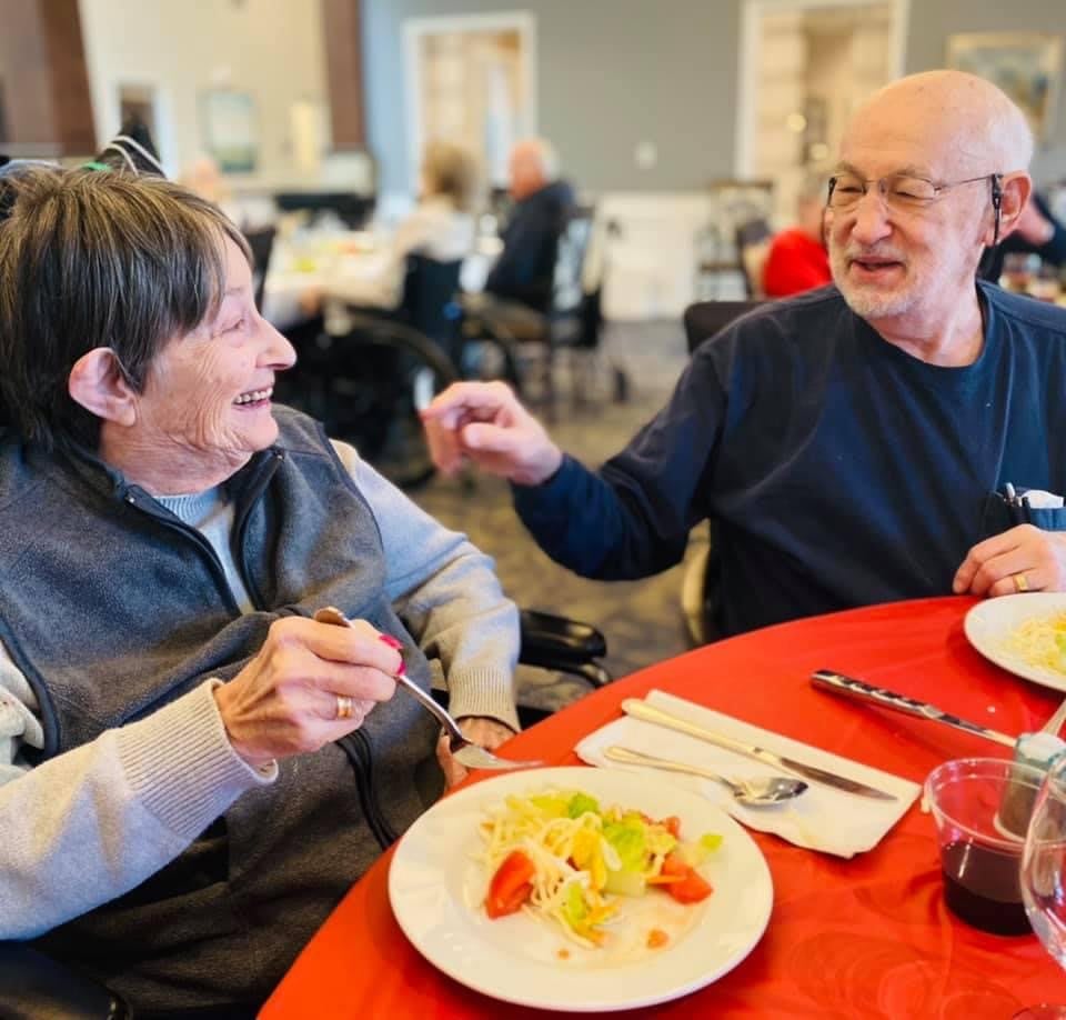Two elderly individuals enjoying a meal and conversation at a restaurant.