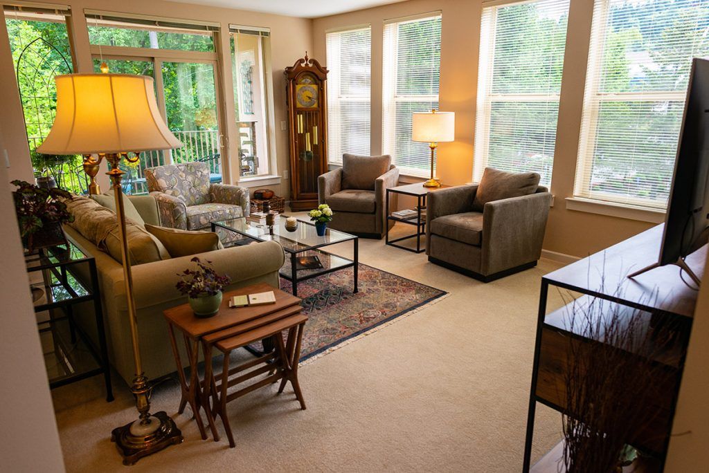 A cozy and well-lit living room featuring comfortable seating, a grandfather clock, and modern decor.