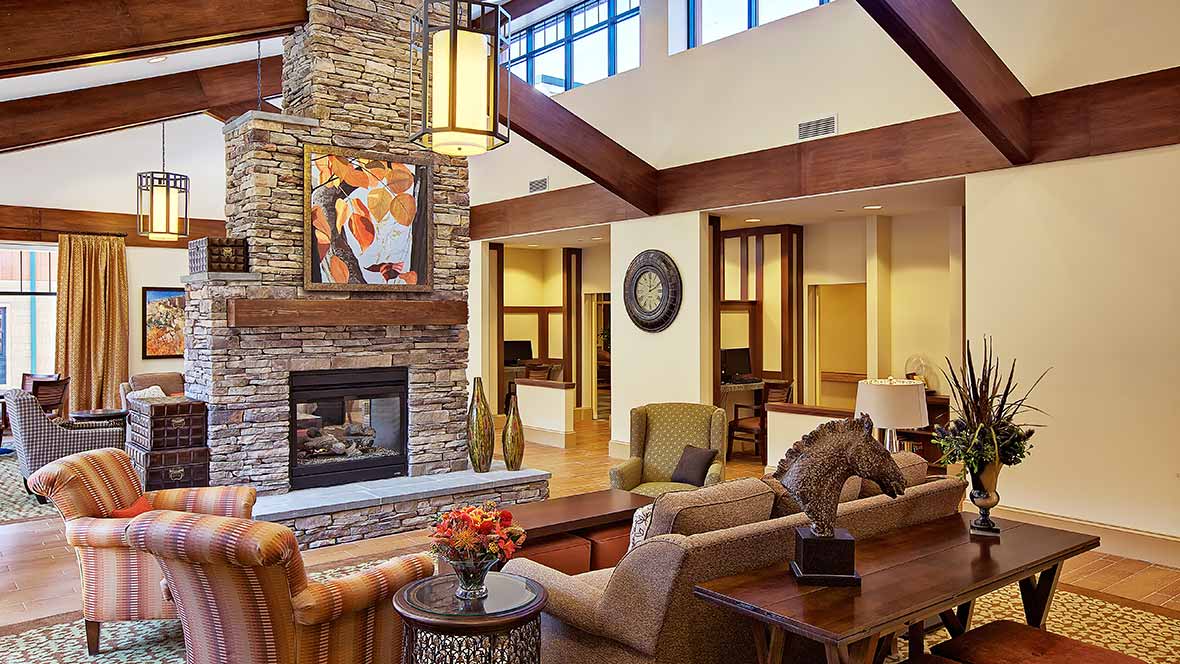 A stylish living room features a stone fireplace, elegant furniture, and modern decor with wooden beams.