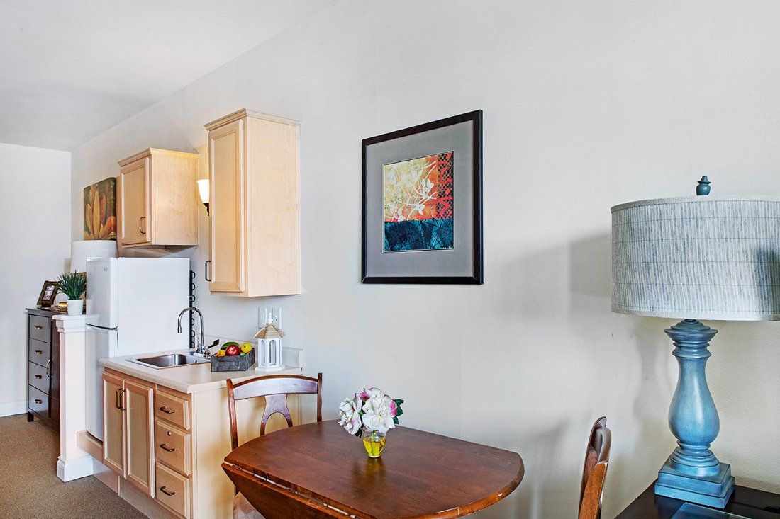 A cozy kitchen and dining area featuring a small wooden table set and a framed artwork on the wall.
