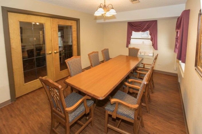 A well-appointed conference room with a long wooden table and several chairs.
