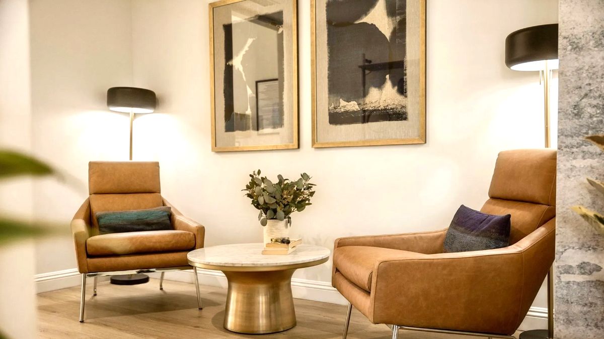 A modern living room with stylish armchairs, a round coffee table, and abstract artwork on the wall.