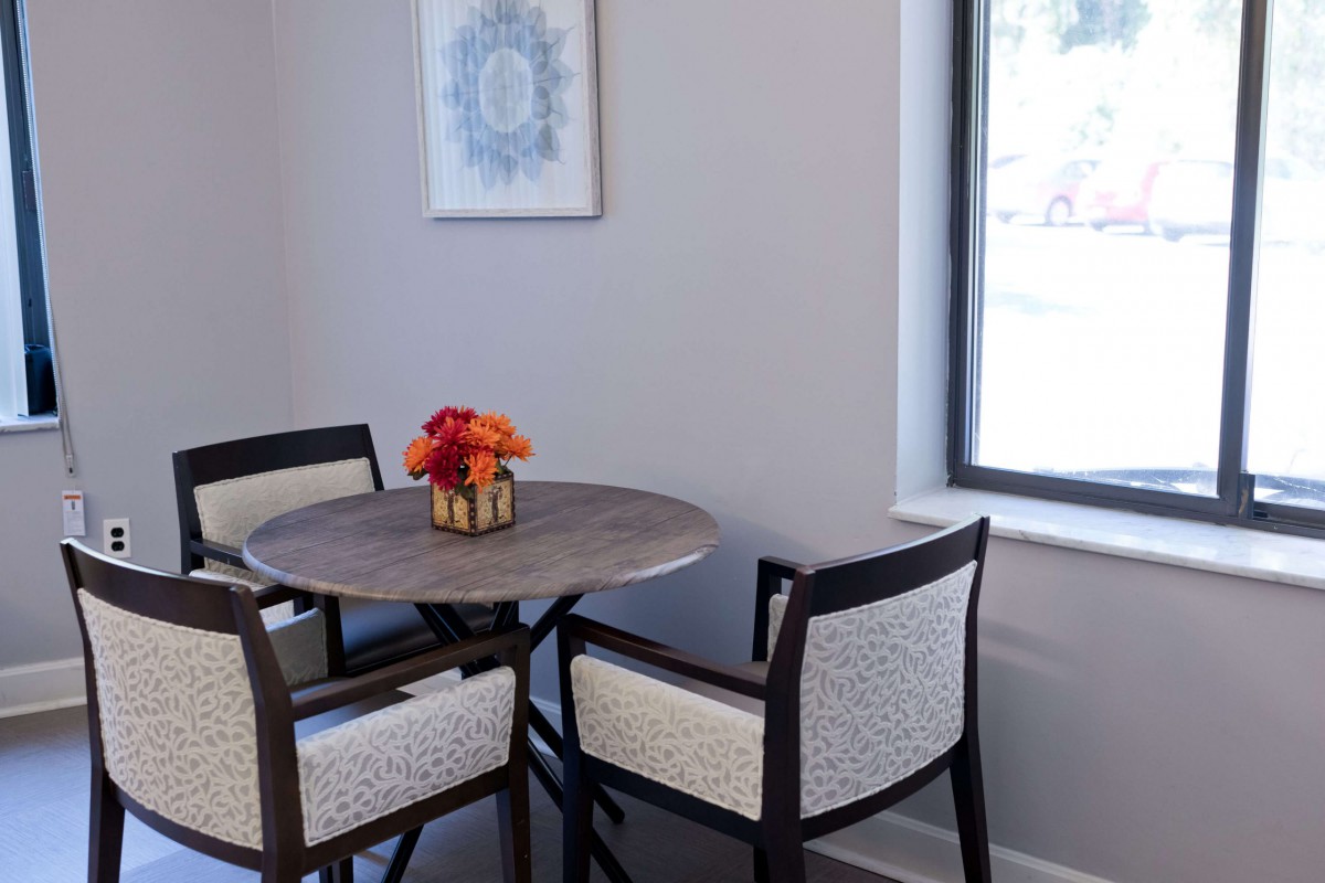 A cozy dining nook with a round table and chairs, adorned with a vase of flowers by the window.
