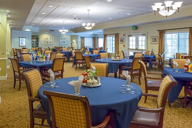 A spacious and elegantly decorated dining room with blue tablecloths and neatly arranged tables.