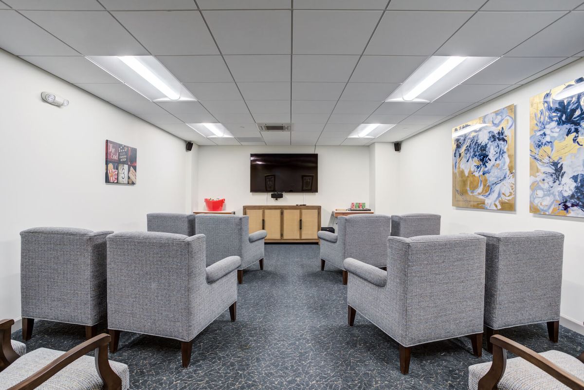 A modern waiting room with arranged seating, a television, and artwork on the walls.