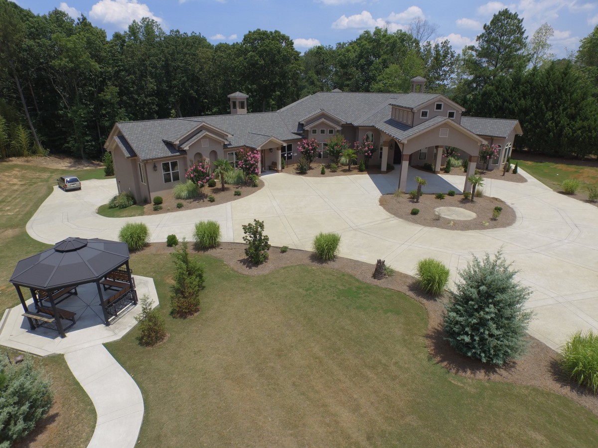 Aerial view of a large mansion with a circular driveway and landscaped surroundings.