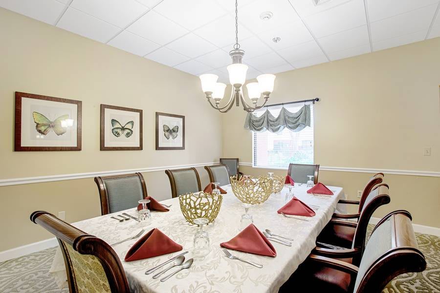 A formal dining room set with a large table, ornate chairs, and decorative butterfly artwork on the walls.