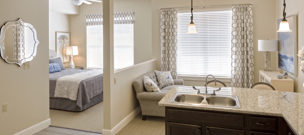 Modern open-layout apartment with a kitchen, living area, and adjacent bedroom.