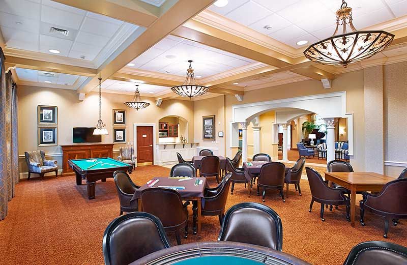 A spacious game room featuring a pool table and several tables with chairs, designed for recreation and relaxation.