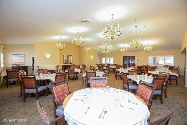 A spacious and elegant dining room with neatly arranged tables and chandeliers.
